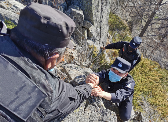 2020年4月18日，民警协同配合攀爬岩石开展一线巡逻。张家旭 摄